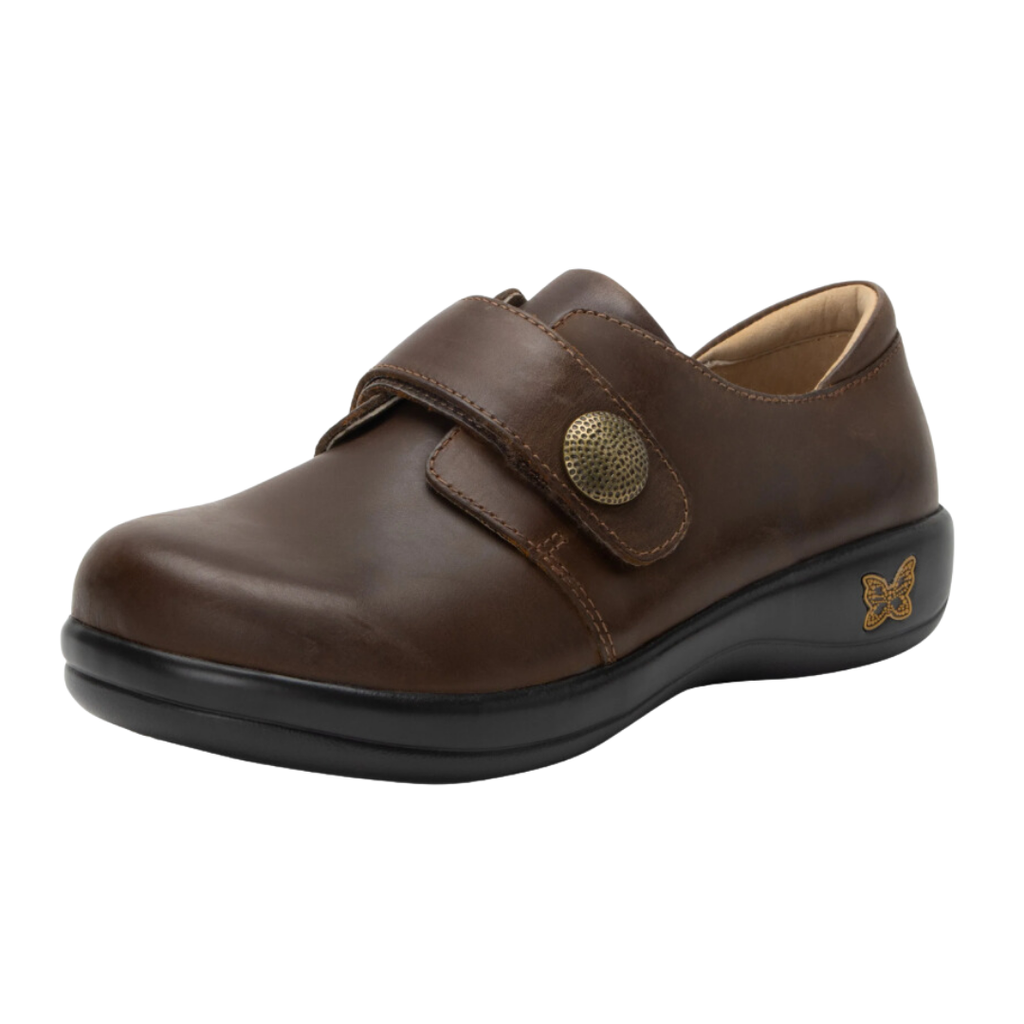 Alegria Women’s Joleen Slip-On Shoe in Oiled Brown side view showcasing the premium leather upper with subtle shine, adjustable hook-and-loop strap, decorative button detail, mild rocker outsole, and professional slip-on design built for comfort and stability.