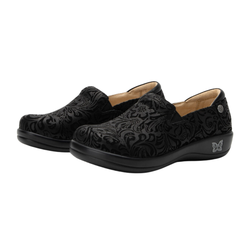 Alegria Women’s Keli Slip-On Shoe in Black Emboss Paisley side view showcasing the stain-resistant embossed leather upper, professional slip-on silhouette, padded collar, mild rocker sole, and slip-resistant outsole designed for lasting comfort and workplace stability.