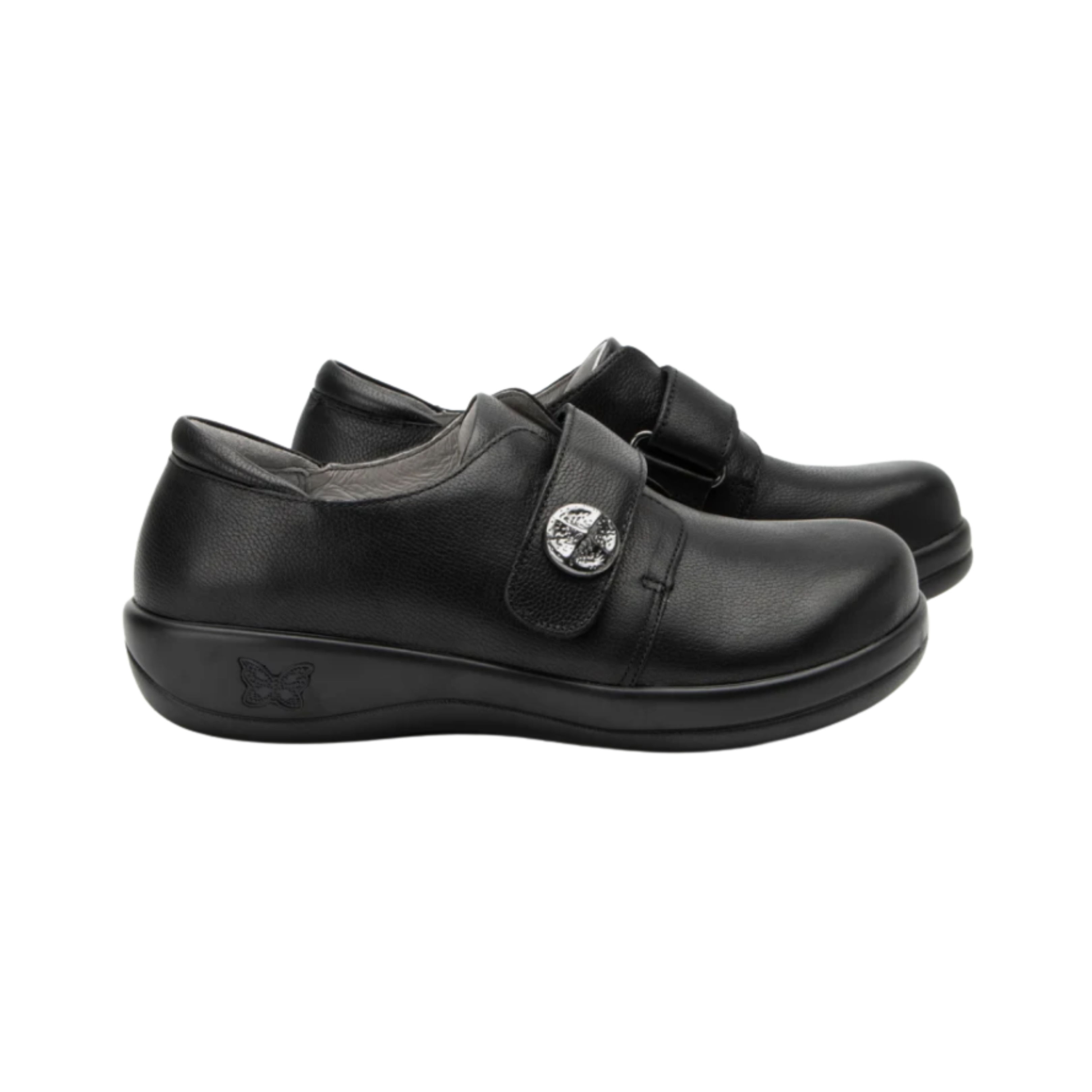 Alegria Women’s Joleen Slip-On Shoe in Upgrade Black side view showcasing the premium leather upper with subtle shine, adjustable hook-and-loop strap, decorative button detail, mild rocker outsole, and professional slip-on design built for comfort and stability.