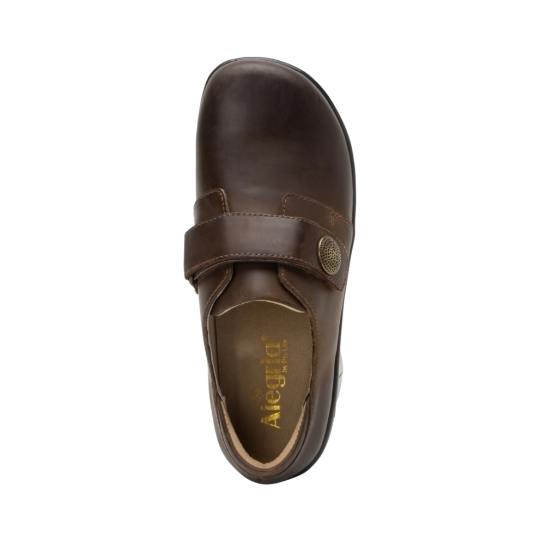 Alegria Women’s Joleen Slip-On Shoe in Oiled Brown top view showcasing the premium leather upper, hook-and-loop strap with decorative button, spacious foot opening, soft lining, and removable Alegria footbed featuring cork, memory foam, and polyurethane cushioning.