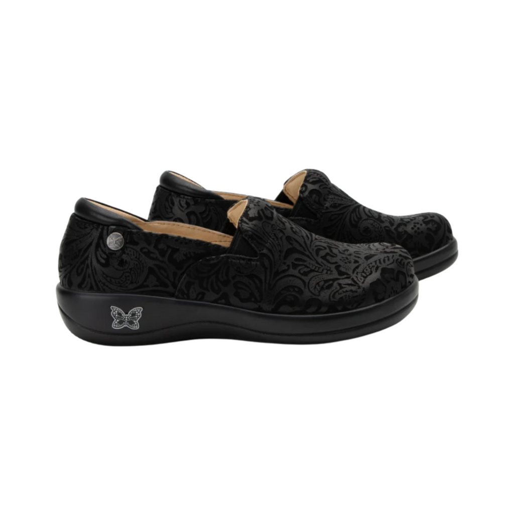 Alegria Women’s Keli Slip-On Shoe in Black Emboss Paisley side view showcasing the stain-resistant embossed leather upper, professional slip-on silhouette, padded collar, mild rocker sole, and slip-resistant outsole designed for lasting comfort and workplace stability.