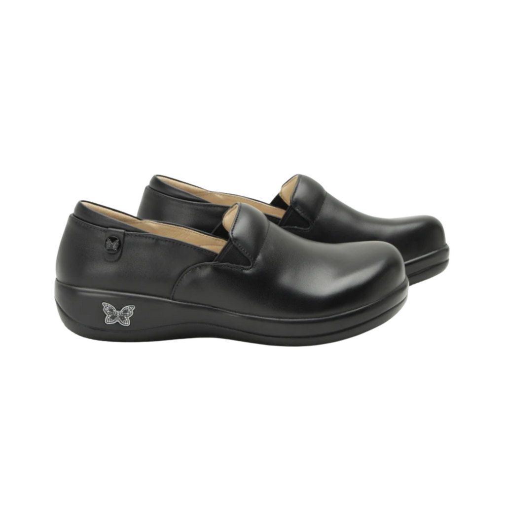 Alegria Women’s Keli Slip-On Shoe in Black Nappa side view showcasing the stain-resistant embossed leather upper, professional slip-on silhouette, padded collar, mild rocker sole, and slip-resistant outsole designed for lasting comfort and workplace stability.