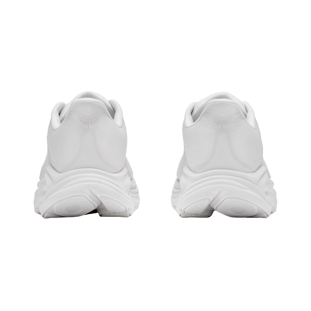 Rear view of the Women's HOKA Clifton 11 in White/White highlighting the cushioned heel, Rearfoot-Focused Active Foot Frame™, reflective details, and durable abrasion rubber outsole designed to provide stability and traction.