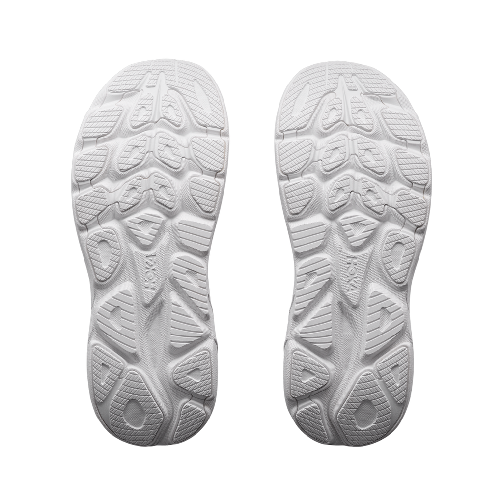 Bottom view of the Women's HOKA Clifton 11 in White/White highlighting the strategically placed abrasion rubber outsole designed to enhance traction and durability while maintaining the shoe's lightweight feel.